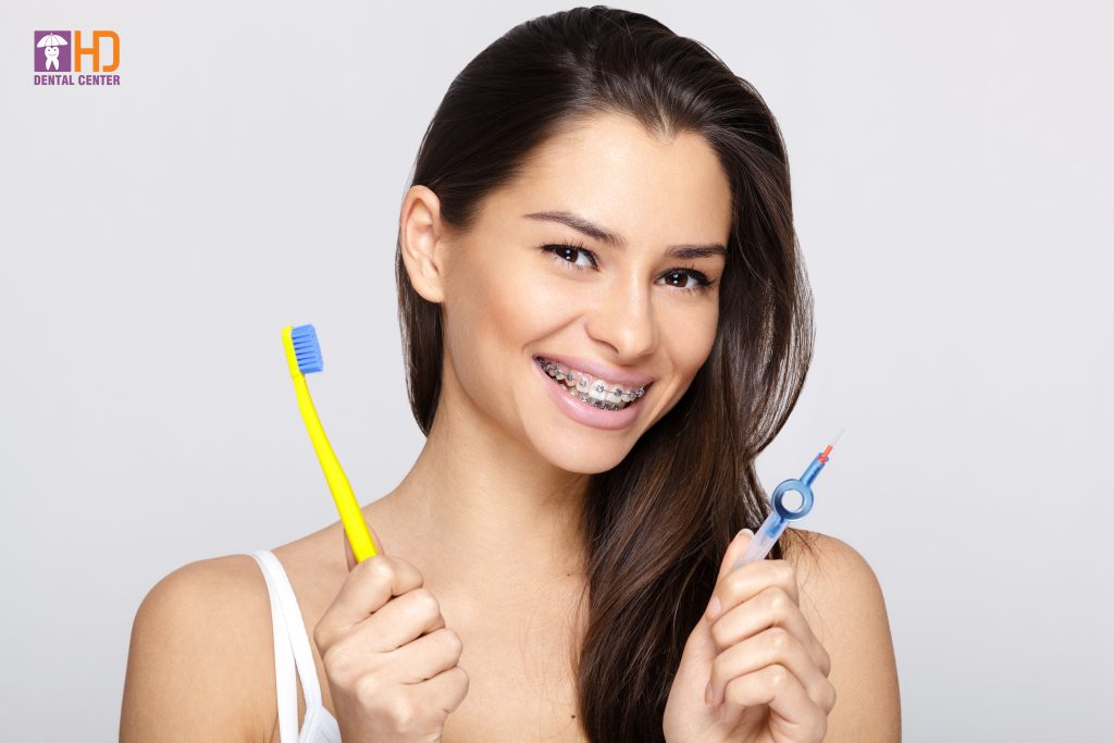 Young woman with braces and toothbrush and braces brush cleaner